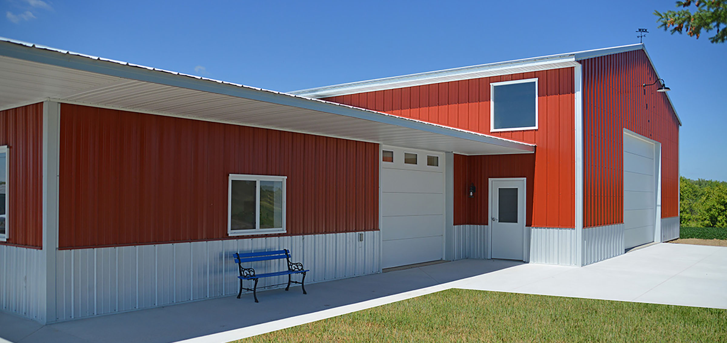 Tundra Built's building services include post frame agricultural buildings such as this red one with white trim and multiple garage doors